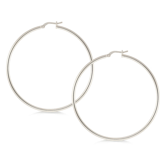 A pair of large, polished silver hoop earrings featuring a sleek and minimalist design. The hoops are circular and feature a smooth, shiny finish that reflects light, enhancing their elegance. The closure mechanism is a simple hinged clasp, ensuring ease of wear while providing a secure fit. These earrings are versatile, suitable for both casual and formal occasions.